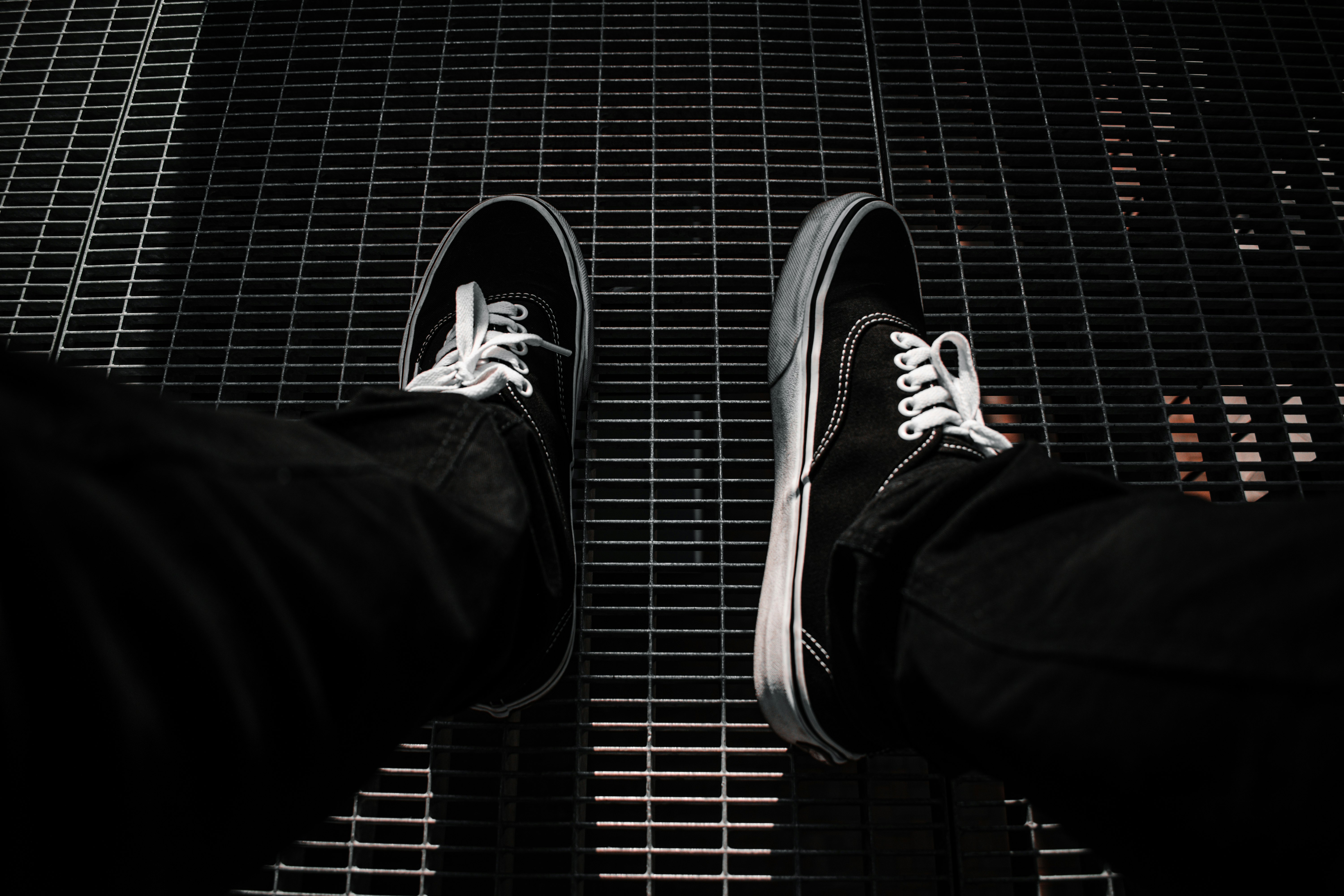 person in black pants wearing black and white sneakers